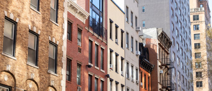 A row of colorful brick residential buildings along a street in Chelsea of New York City