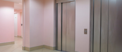 bank of 2 elevators at the base of apartment building lobby with pink walls