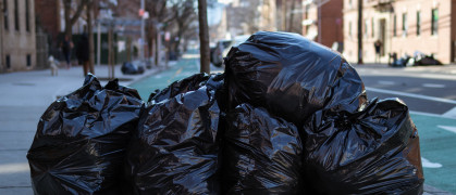 Black garbage bags filled with trash along the street and sidewalk in Astoria Queens of New York City