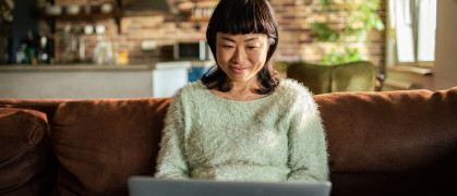 Close up of a young Japanese woman using a laptop on a couch in the living room
