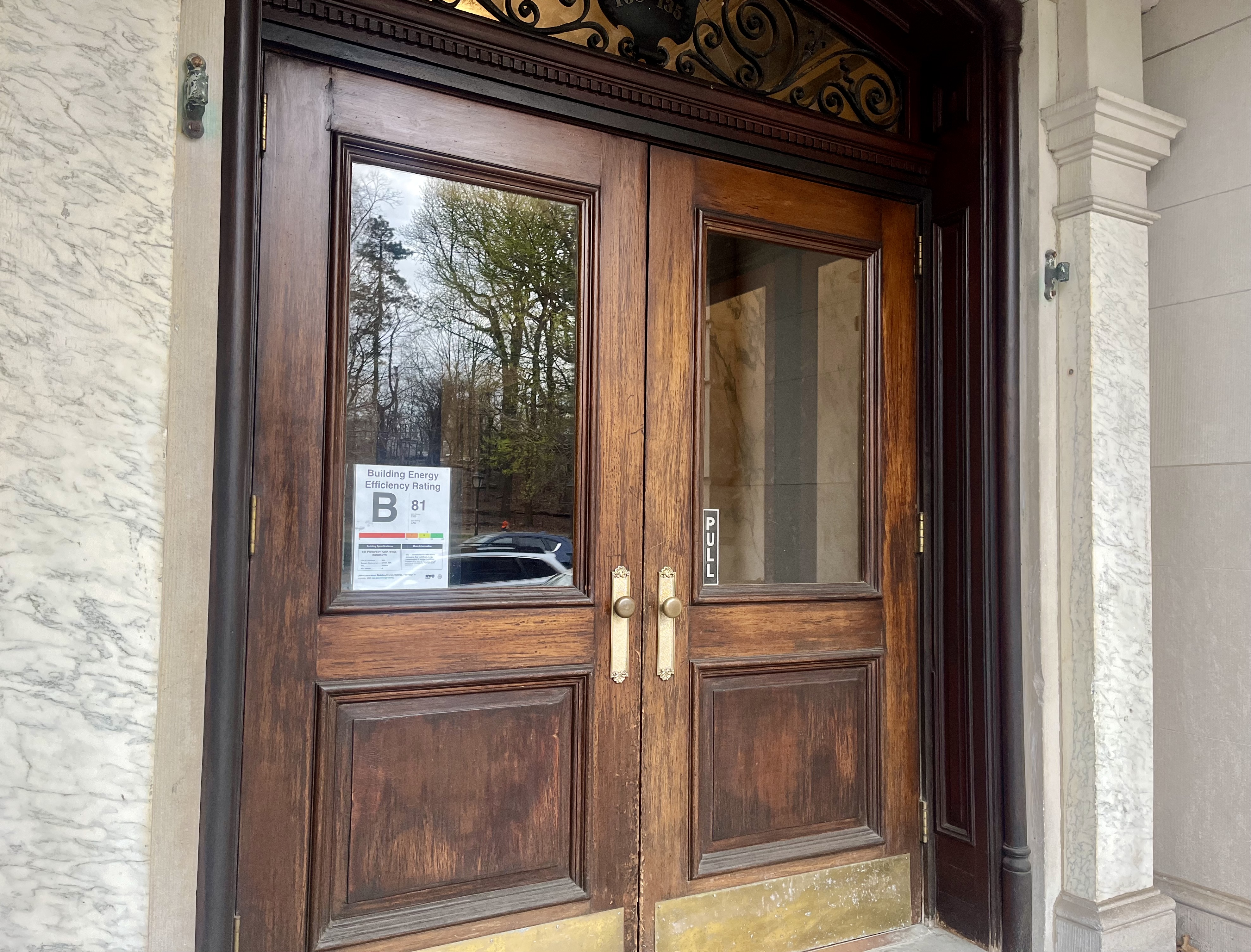 Benchmarking.jpeg Wooden double entry doors of NYC apartment building Brooklyn with B grade energy efficiency notice