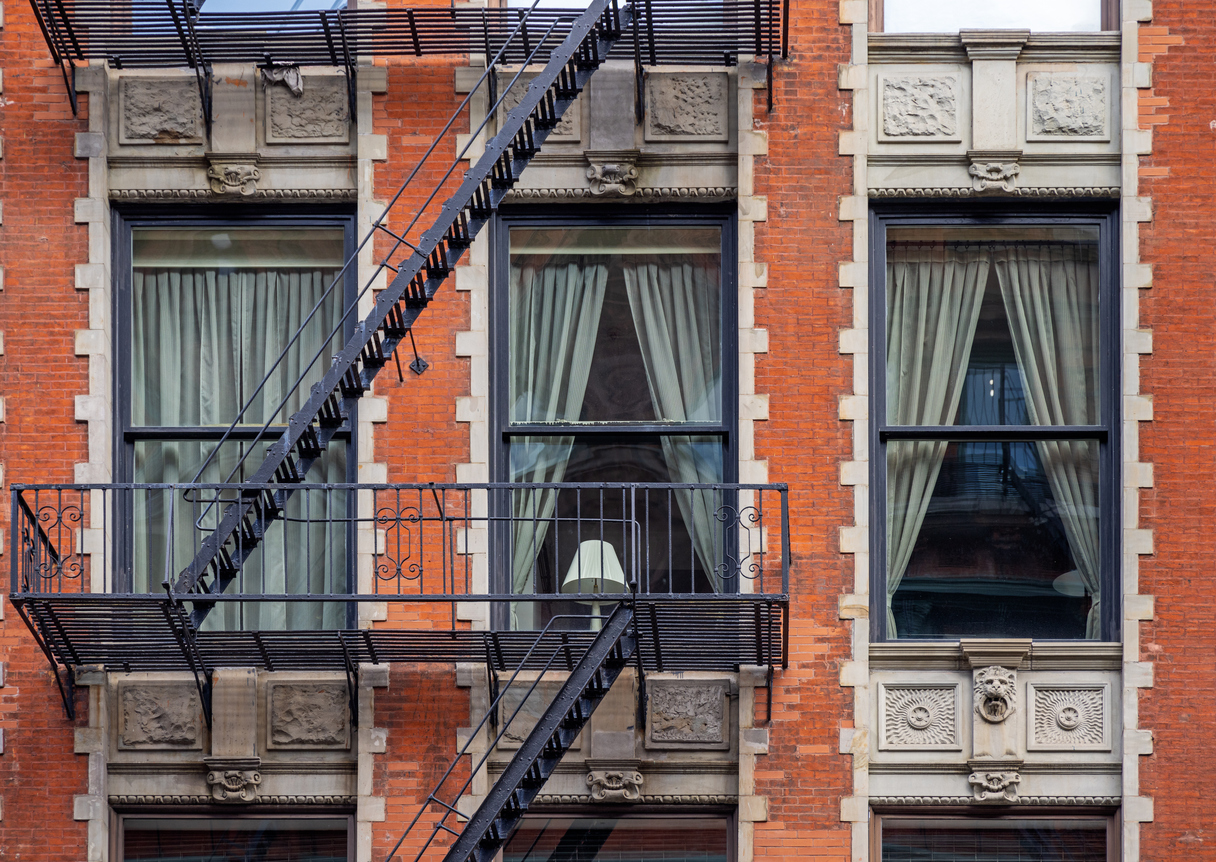 Lamp in a window between fire escape stairs