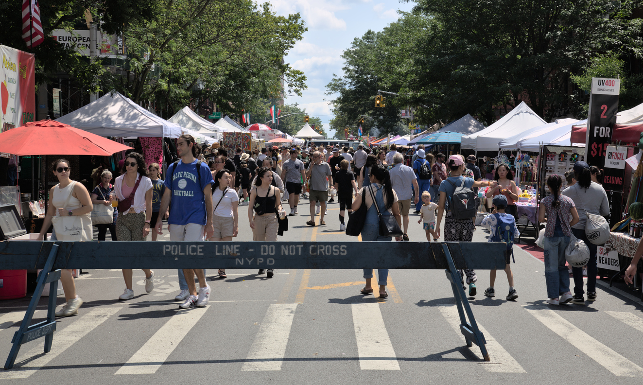Participants walk down closed street during 7th Heaven fair in Park Slope with vendor stalls