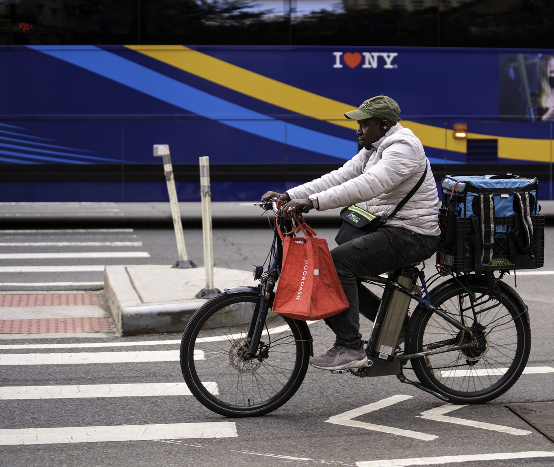 A delivery person on an e-bike rides on Second Avenue in Manhattan. A delivery person on an e-bike rides on Second Avenue in Manhattan.