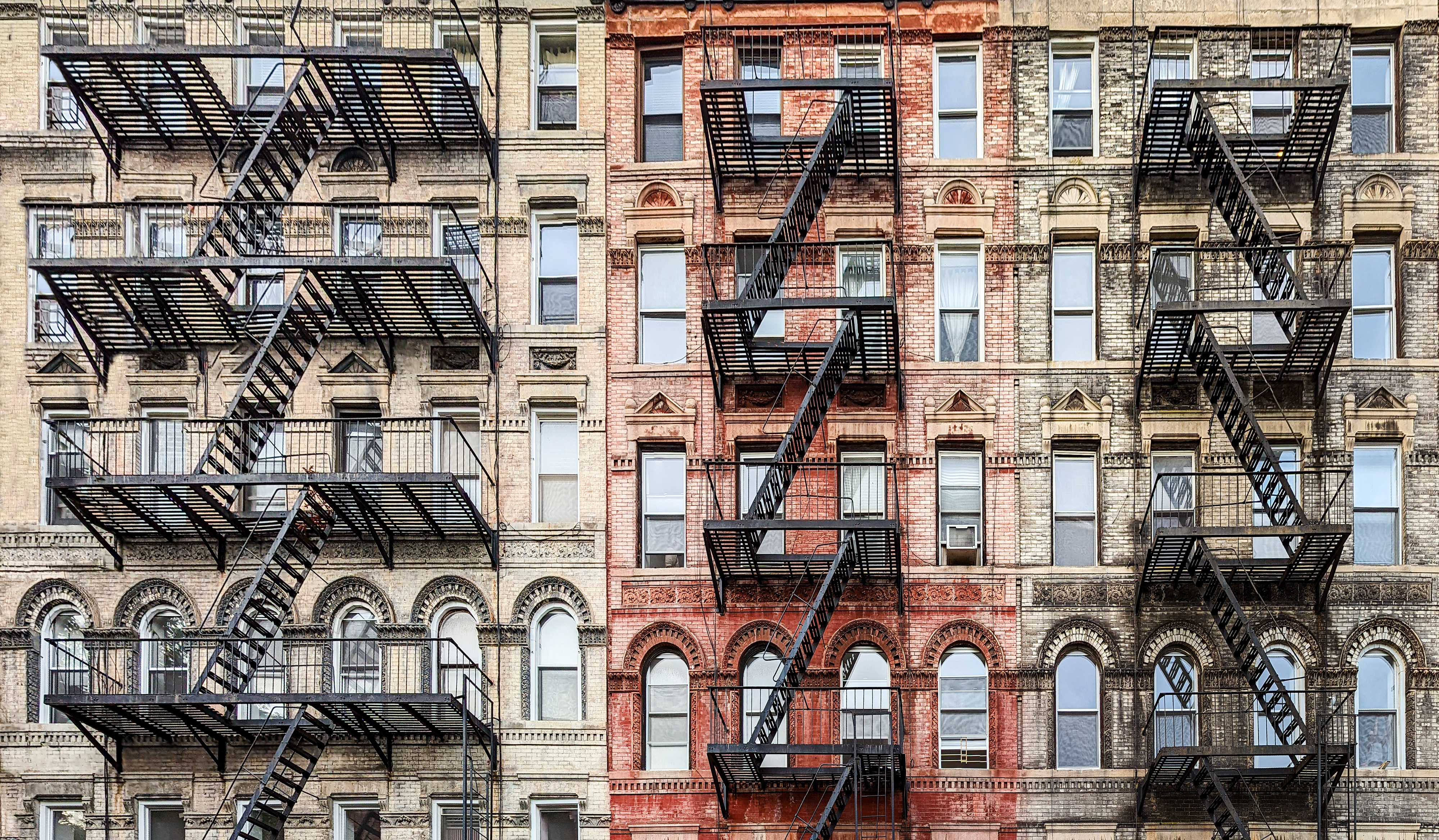 Exterior view of old New York City style architecture apartment building with windows and fire escapes