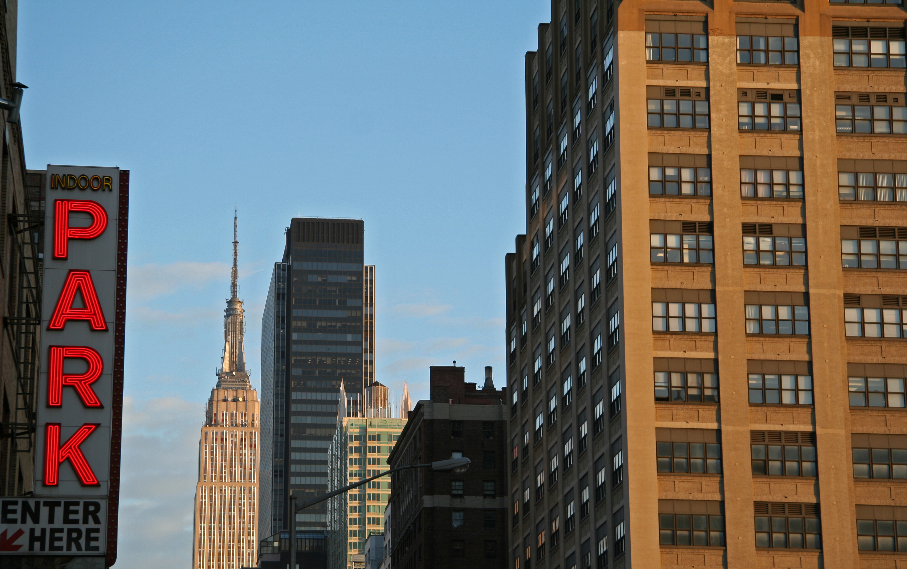 A photo of NYC buildings and a parking garage sign on the left