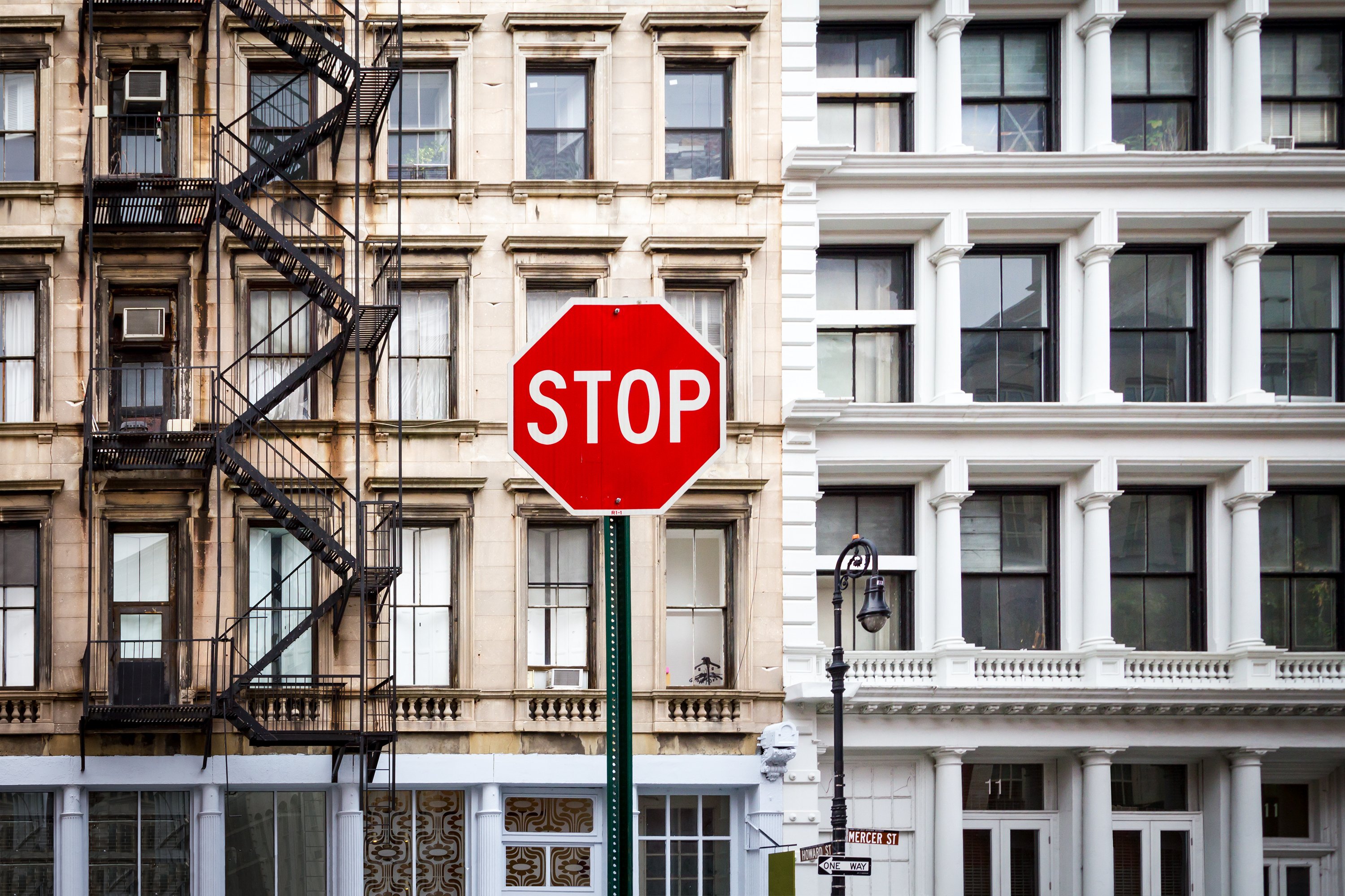 A photo of a stop sign in front of an NYC apartment building. A photo of a stop sign in front of an NYC apartment building.