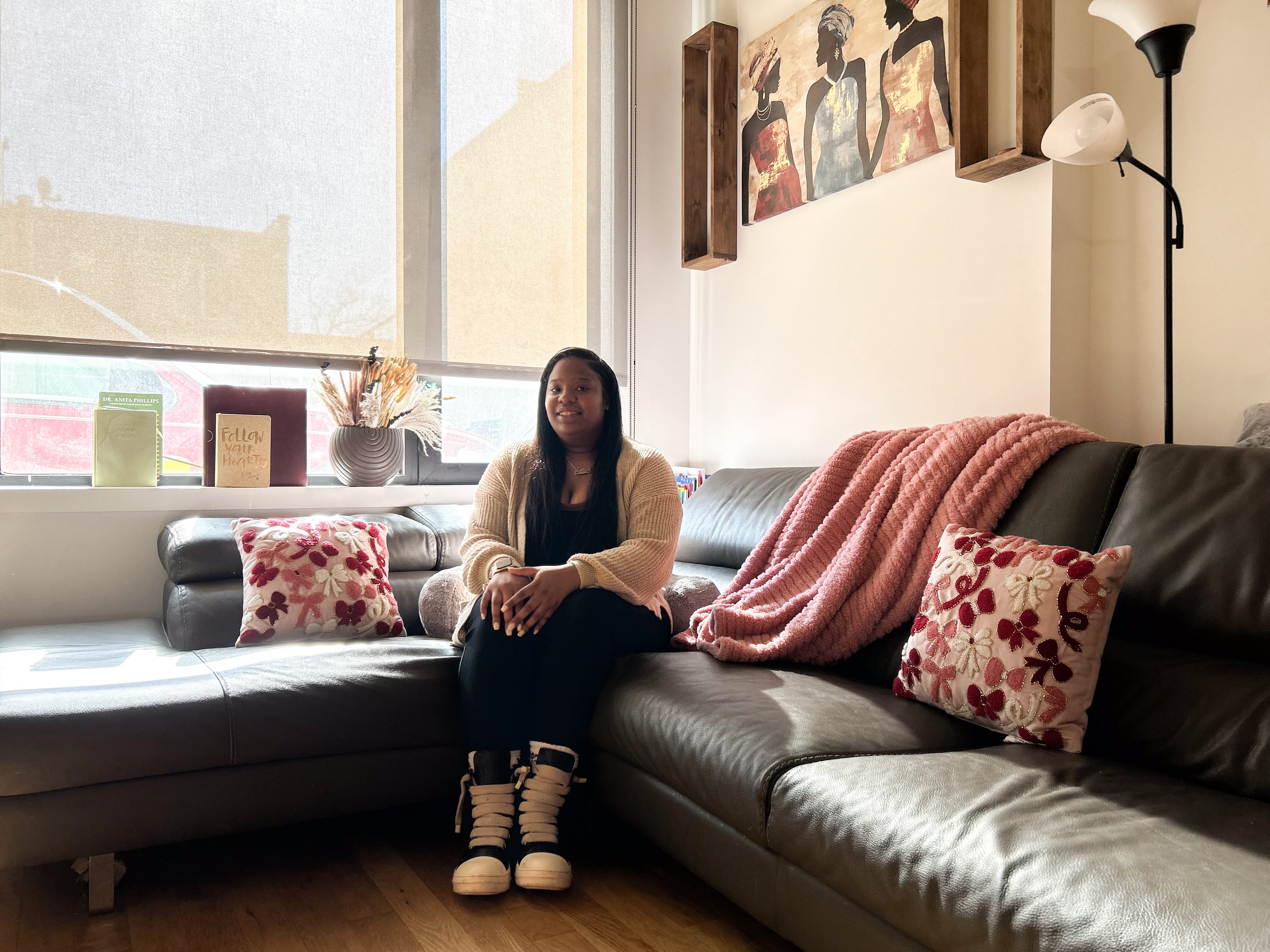 Anasthasia's housing lottery apartment is rent-stabilized, and rent increases are capped annually by a city board. Anasthasia on her couch.