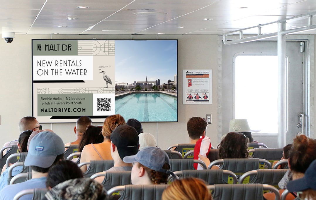 NYC Ferry riders on the East River route see ads for the Malt Drive development. NYC Ferry riders on the East River route see ads for the Malt Drive development.
