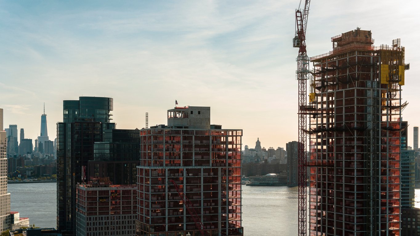 Modern buildings under construction on the waterfront in Greenpoint, Brooklyn with the view of Manhattan with Freedom Tower over the East River. Modern buildings under construction on the waterfront in Greenpoint, Brooklyn with the view of Manhattan with Freedom Tower over the East River.