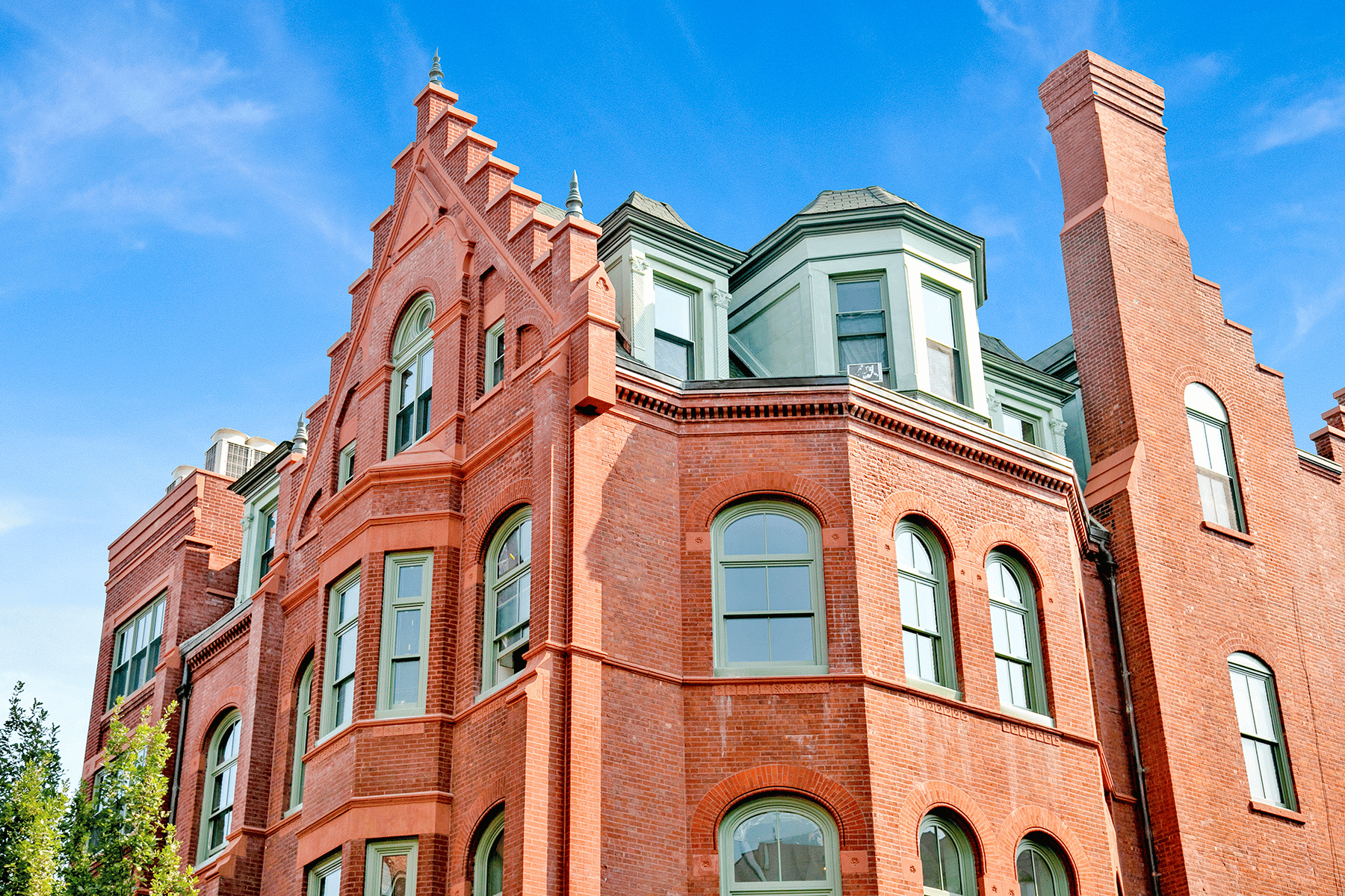 Red brick building with green gables reaching into the sky