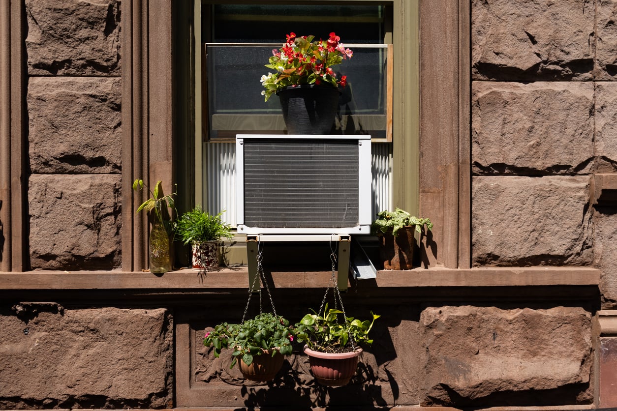 Window air conditioner with potted plants in a brick building
