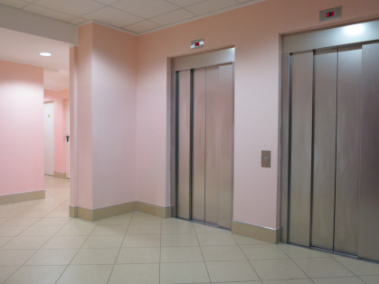 ReserveStudy.jpg bank of 2 elevators at the base of apartment building lobby with pink walls