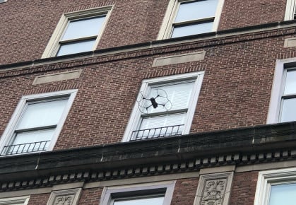 A drone flies toward a building for a facade inspection.