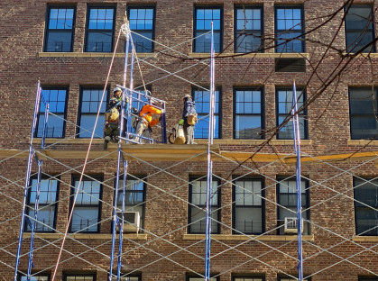 Four workmen in safety gear rig scaffolding in front of a Manhattan apartment building in 2022.