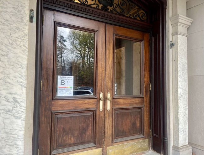 Wooden double entry doors of NYC apartment building Brooklyn with B grade energy efficiency notice