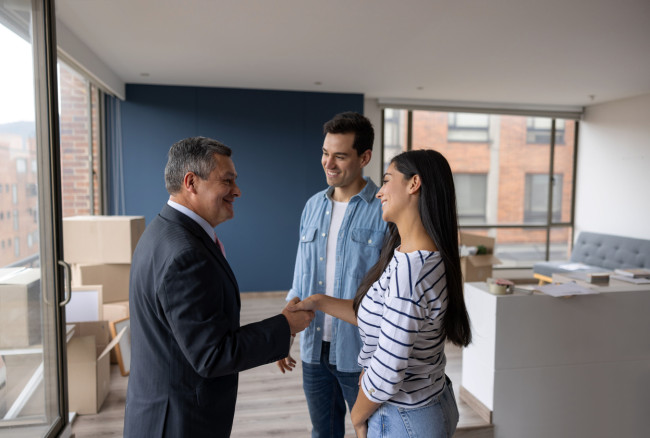 Real Estate Agent selling an apartment to a couple and closing the deal with a handshake stock photo