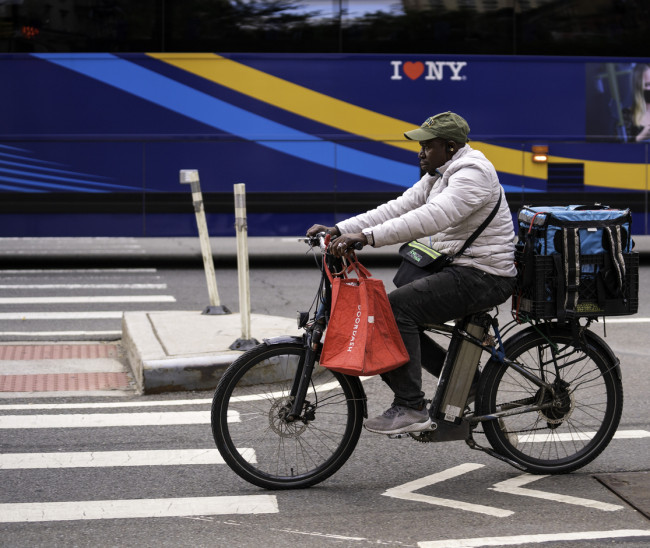 A delivery person on an e-bike rides on Second Avenue in Manhattan.