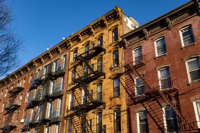 Looking up at a row of colorful old brick residential buildings with fire escapes along a street in Williamsburg Brooklyn of New York City Looking up at a row of colorful old brick residential buildings with fire escapes along a street in Williamsburg Brooklyn of New York City