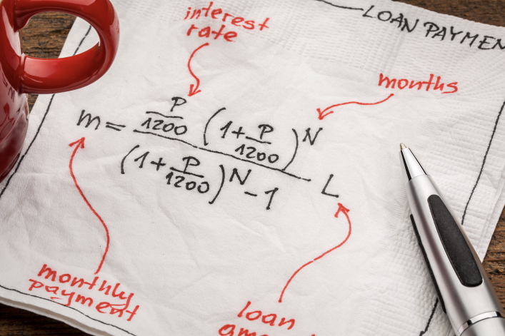 loan payment equation sketched on a white napkin with a cup of coffee