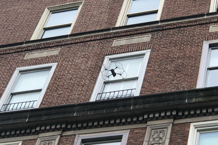 A drone flies toward a building for a facade inspection.