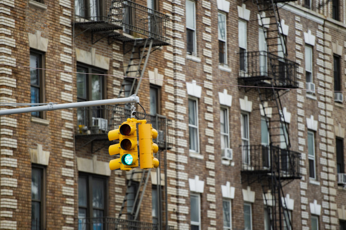 Close-up view of a traffic light and some buildings on background with windows and emergency stairs. Bronx District, 