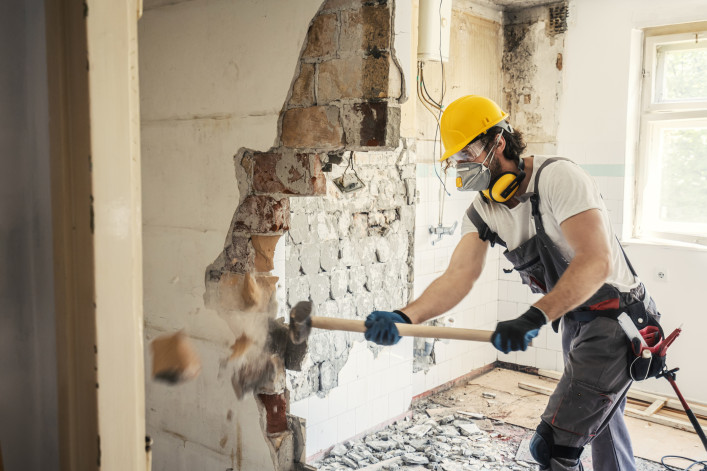 Worker using hammer to demo a wall 