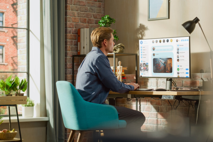 Young Handsome Man Using Desktop Personal Computer to Check Social Media Wall Feed, Live Stream Videos, Posts, Pictures. Mock-up Posts: Creativity, Tech, News, Science, Lifestyle Content