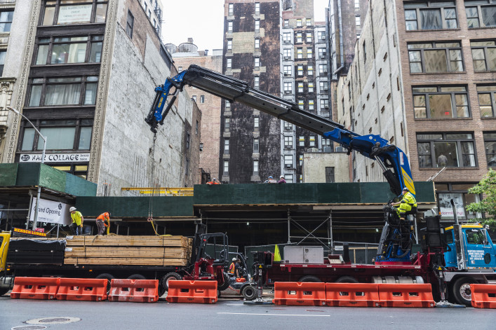 Construction works on Fifth Avenue (5th Avenue) with heavy industrial machines and workers in Manhattan in New York City, USA