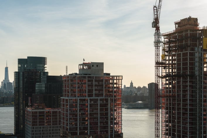 Modern buildings under construction on the waterfront in Greenpoint, Brooklyn with the view of Manhattan with Freedom Tower over the East River. Modern buildings under construction on the waterfront in Greenpoint, Brooklyn with the view of Manhattan with Freedom Tower over the East River.