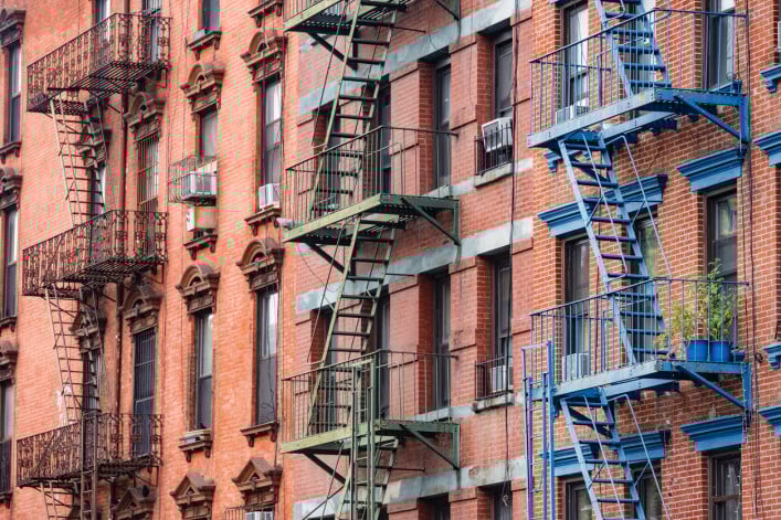 This is a photograph of brightly painted fire escapes on historic brick buildings in the Lower East Side of Manhattan.