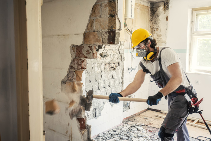 Worker using hammer to demo a wall