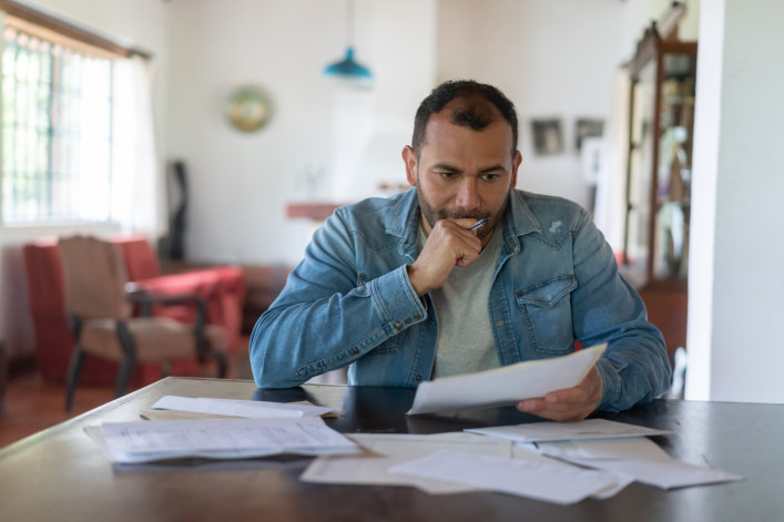 A man looks over several documents and looks concerned.