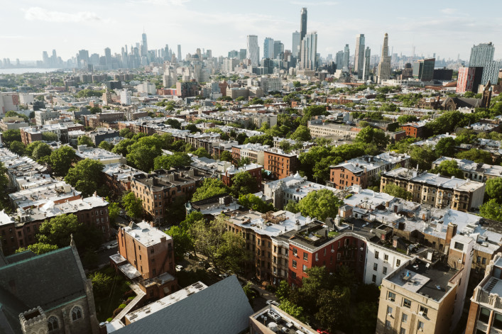 A view of short Brooklyn buildings with the Manhattan skyline in the background