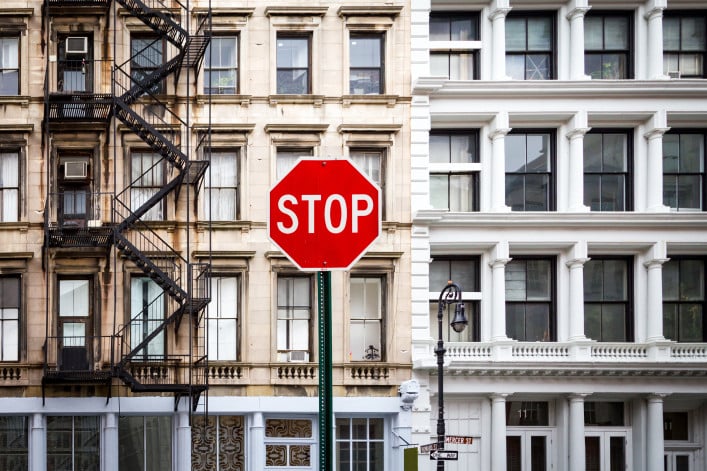 A photo of a stop sign in front of an NYC apartment building.