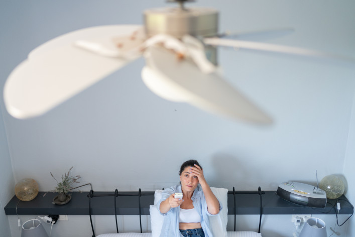 Woman using remote control for ceiling fan
