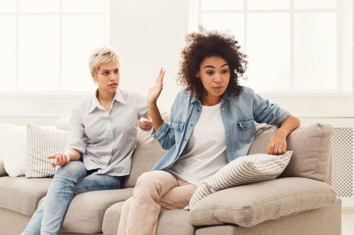 Roommates seated on a couch having an argument
