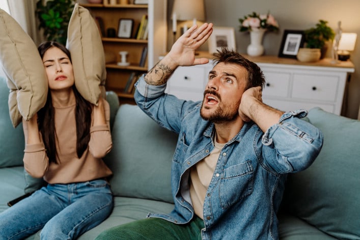 Couple sitting on couch upset by loud neighbors