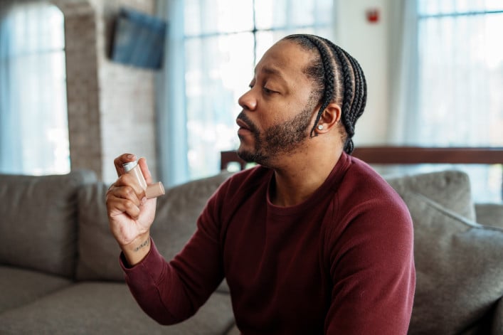 Man at home using inhaler