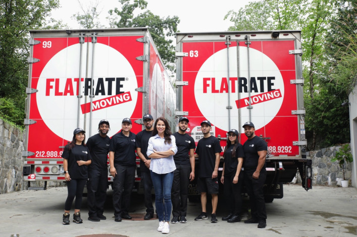 Team members and founder standing in from of two FlatRate Moving trucks