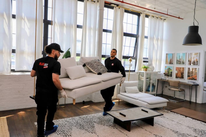 Flat Rate movers in uniform carrying a couch