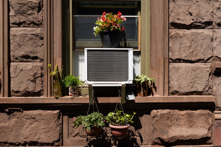 Window air conditioner with potted plants in a brick building