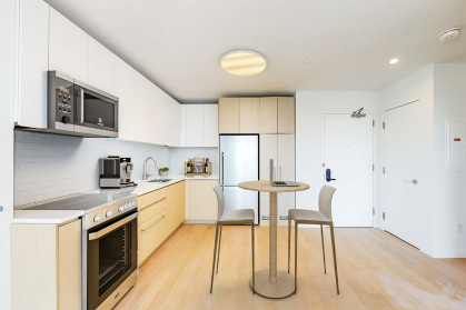 NYC apartment interior with wood floor, stainless steel appliances and barstools