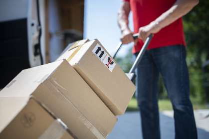 Shot of unrecognizable delivery guy pushing cart full of parcels. stock photo