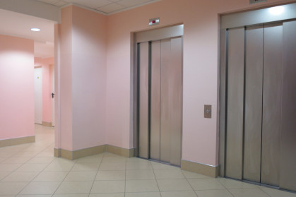bank of 2 elevators at the base of apartment building lobby with pink walls