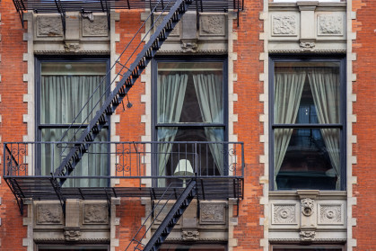 Lamp in a window between fire escape stairs