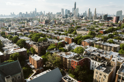 A view of short Brooklyn buildings with the Manhattan skyline in the background