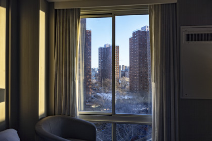 Several skyscraper city apartment buildings viewed through a generic upper east side Manhattan, New York City hotel bedroom window just after dawn sunrise.