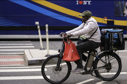 A delivery person on an e-bike rides on Second Avenue in Manhattan.