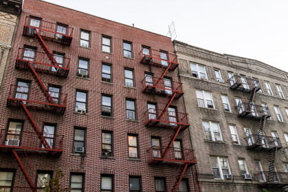 Brick apartment condo building exterior architecture in Fordham Heights center, Bronx, NYC, Manhattan, New York City with fire escapes, windows, ac units in evening stock photo